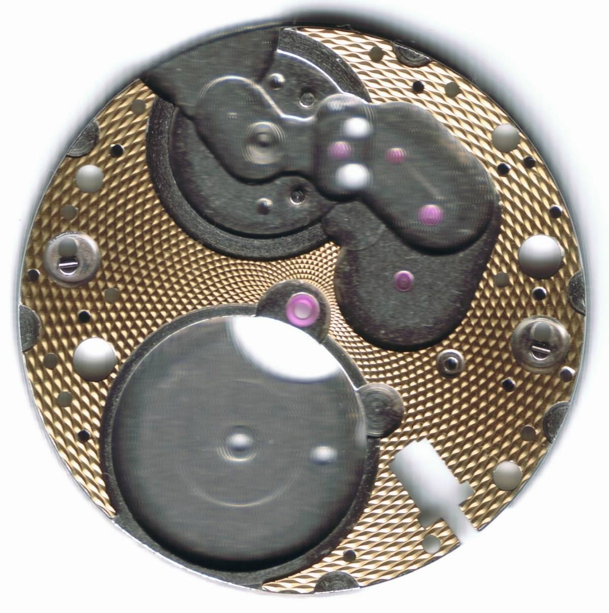 A barleycorn guilloche pattern cut into the brass main plate of a German mechanical watch movement, scanned at high resolution.