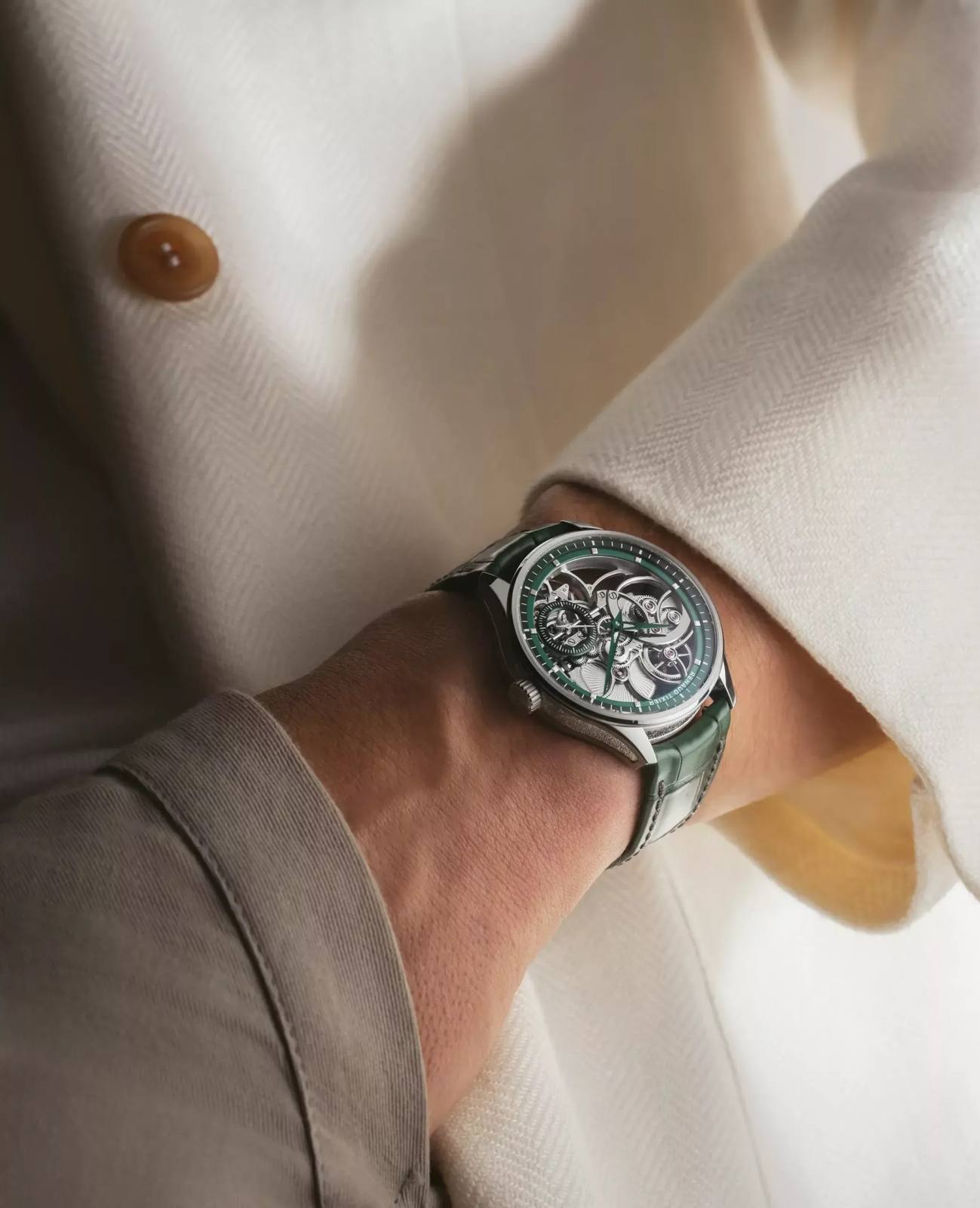 Renaud Tixier Monday Skeleton green edition worn on a wrist under a cream jacket cuff.